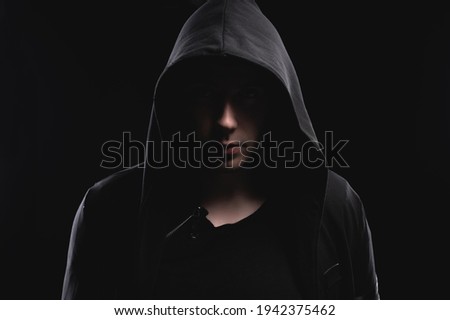 Studio portrait of a man in a hood, a shadow hides his face. Anonymity shadow economy and evasion from the law Royalty-Free Stock Photo #1942375462