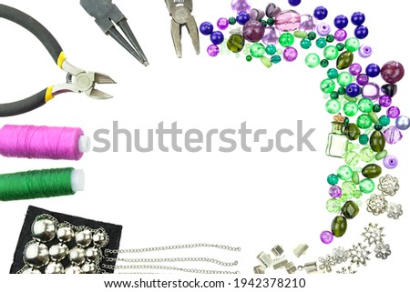 Layout of green and violet beads, sewing threads and other jewellery suppliers isolated on a white background. Frame for text. Selective focus.