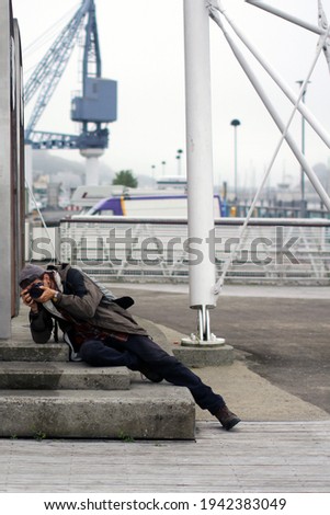 Skilled photographer lies down on the steps for the best perspective. Photographic tourist takes pictures in an Irish harbor.