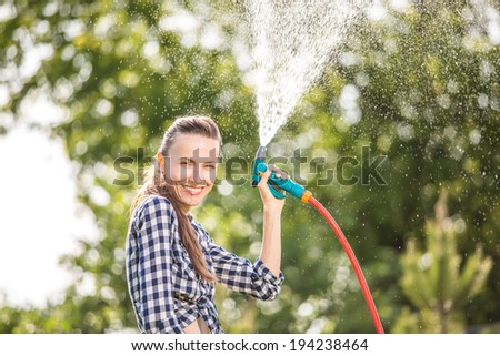 Attractive female water plants with garden hose on a sunny summer day