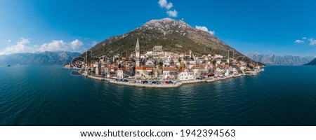Panorama bird's eye view of small island in Adriatic sea, covered by greenery, traditional Balkan style architecture, ancient buildings and cathedral. Mountains in the background