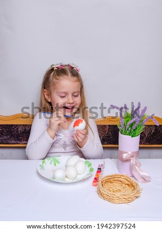 A little girl paints chicken eggs with a brush. The religious Orthodox holiday of Easter. Preparing for the holiday.