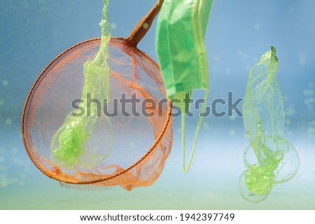 scoop-net near medical mask and plastic bags in water, ecology concept