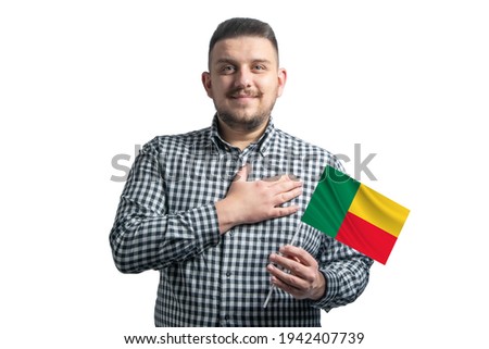 White guy holding a flag of Benin and holds his hand on his heart isolated on a white background With love to Benin.