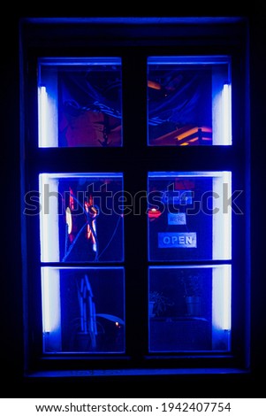 Bar or shop window at night. Showcase detail with blue neon LED lights. Open sign on a window. Moody, dark, dirty place with decorations. Night live entertainments concept. Vertical, close up