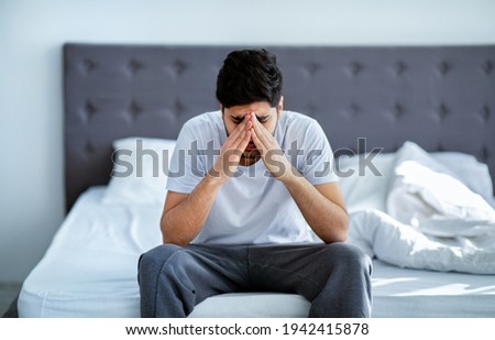 Male depression. Unhappy arab man sitting on bed and thinking about problems, closing face with hands Royalty-Free Stock Photo #1942415878