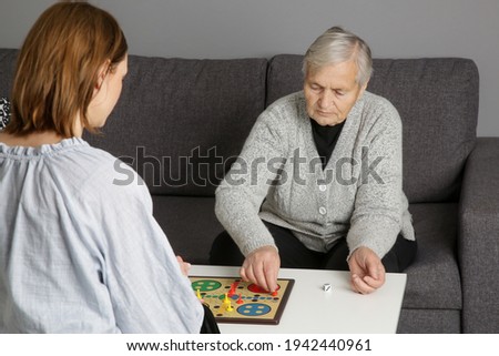 Senior woman playing board game with granddaughter or care giver. Preventing Alzheimer’s disease and dementia—or slowing its progress through leisure time and active social lives.