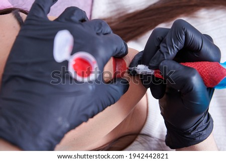 Closeup shot of a woman preparing to undergo the procedure of lip blushing with a tattoo machine Royalty-Free Stock Photo #1942442821