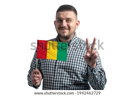 White guy holding a flag of Guinea and shows two fingers isolated on a white background.