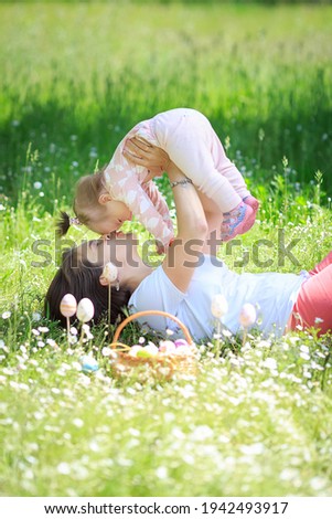 Happy mother and little child hugging kissing in spring park on nature. Mom throws her beloved healthy daughter up in her arms. Family on vacation. Easter. Woman loves her girl. Family games concept