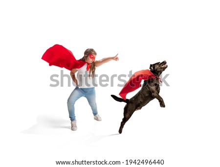 Child pretending to be a superhero with her super dog isolated on white studio background