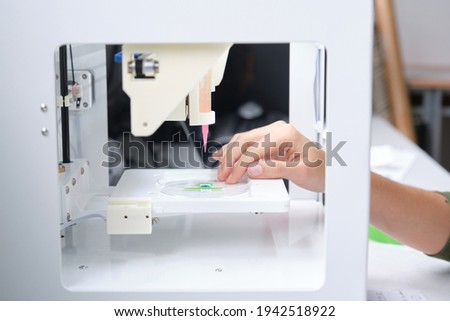 Researcher getting 3D bioprinter ready to 3D print cells onto an electrode. Biomaterials, tissue engineering concepts. Royalty-Free Stock Photo #1942518922