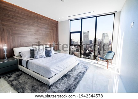 Modern and luxurious bedroom with white ceiling and wood accents with views of Tokyo skyline, particularly Minato ward. Condo or Hotel accomodation. Royalty-Free Stock Photo #1942544578