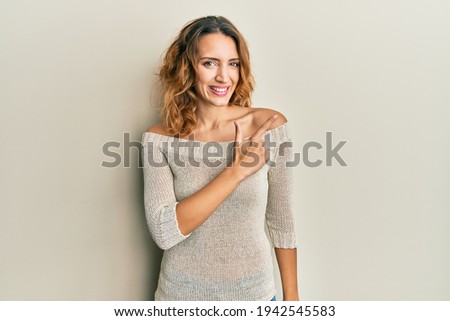 Young caucasian woman wearing casual clothes smiling cheerful pointing with hand and finger up to the side 