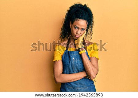 Middle age african american woman wearing professional apron thinking looking tired and bored with depression problems with crossed arms. 