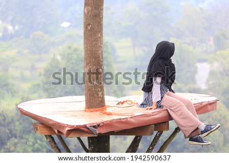 A woman in a veil poses in a tree house. Islamic fashion which is trendy and casual Royalty-Free Stock Photo #1942590637