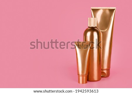 Golden bottles, cosmetic products on pink background. Luxury beauty style. Gold cosmetic containers. Mockup bottles, cosmetics branding, hair or body care concept. Copy space, empty place for text