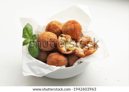 Arancini are Italian rice balls that are stuffed with meats and mozarella, coated with bread crumbs and deep fried.  Selective focus Royalty-Free Stock Photo #1942603963