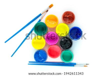 jars of colorful paint with open lids and brushes, top view close up, isolated object