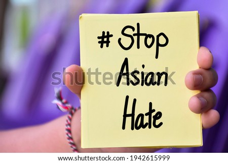 English texts '#Stop Asian Hate' on yellow sticky note in left hand, concept for calling international community to stop the hatred of the Asian people that have caused spreading of the covid-19.