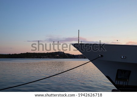 Prow of a ship anchored by the doc with pastel color early evening sky over calm Adriatic Sea