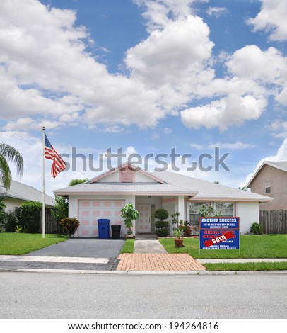 American Flag Sold Real Estate (another success let us help you buy sell your next home) sign Suburban Home Landscaped front yard residential neighborhood USA Blue Sky Clouds