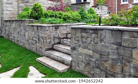 Natural stone steps and retaining wall in the garden. Royalty-Free Stock Photo #1942652242