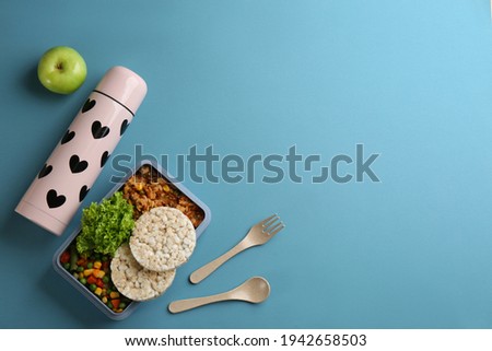 Thermos and lunch box with food on light blue background, flat lay. Space for text