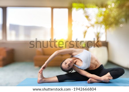 Attractive sporty young woman doing warming up stretching exercises in her home gym.