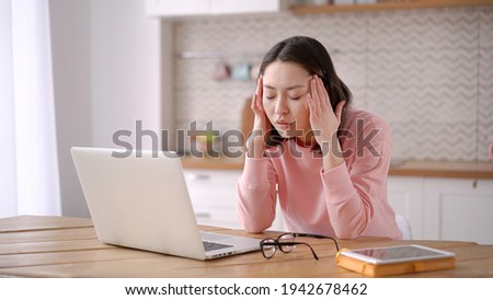 Stressed overworked mixed race business woman working from home take off glasses feel eye strain fatigued from laptop computer. Tired asian freelancer suffer from headache pain, remote work concept Royalty-Free Stock Photo #1942678462