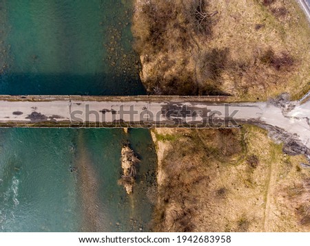 black car on old bridge thought mountain river with green water taken with drone in winter