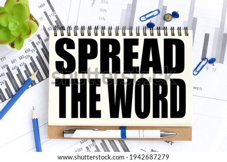 Spread the word. Business concept. text on white notepad paper on a light background near financial charts