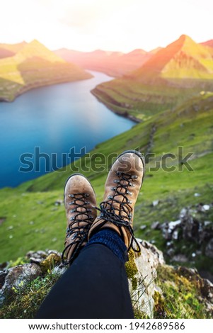 Boots of lonely tourist over majestic fjords of Funningur, Eysturoy island, Faroe Islands. Landscape photography