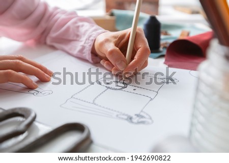 The designer draws a sketch of a woman's bag on paper at the workplace. Fashion design.