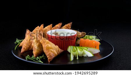 side view Food photography of traditional samosa on wooden platter iftaar with dramatic art direction. black background