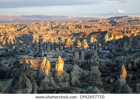 Volcanic rock formations with the Volcano Erciyes in the background, Goreme, Cappadocia, Turkey Royalty-Free Stock Photo #1942697710