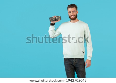 stylish smiling young man holding wireless speaker listening to music colorful style happy mood isolated on blue background