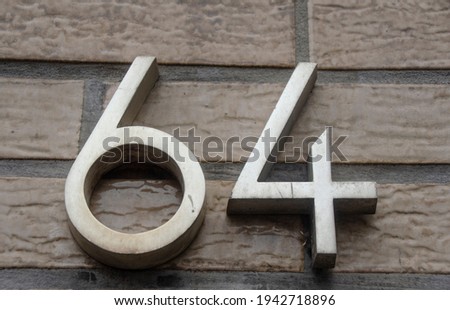 A sign on a wall with the number sixty-four-64