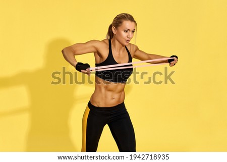 woman in black sportswear exercising with rubber resistance band