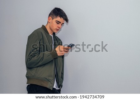 teenager boy with mobile phone at home wall isolated