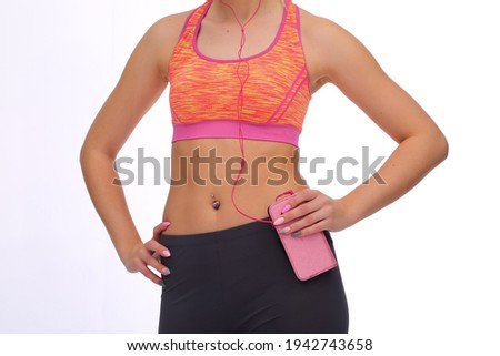Fitness trainer athletic body. Perfect belly. Ornament in the navel. Music during training