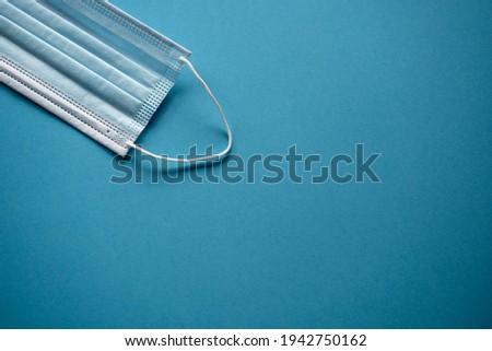 medical protective blue face mask lies on the edge against a blue background taken in natural daylight