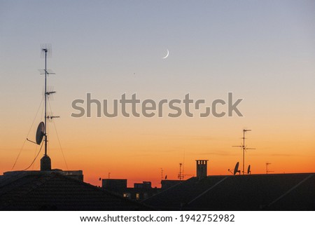A stunning golden sunset of San Siro in Milan and a waxing crescent moon in the sky