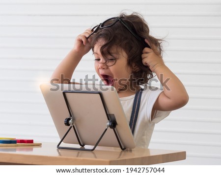 Cute little toddler girl putting glasses on the head while watching movie on the digital tablet. Little girl feeling excited and happy.