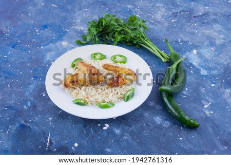 Isolated on galaxy blue background, noodles with fried chicken wings, green hot peppers, coriander. High quality photo