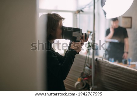 Female director of photography with a film camera on the shooting. Modern filming process of a film, advertising on the set.