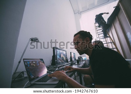 Editing director behind monitors on the set. A video editor edits video online while filming for a playback. Shooting shift, equipment and group. Modern photography technique.