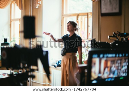 Director at work on the set. The director works with a group or with a playback while filming a movie, advertising, or a TV series. Shooting shift, equipment and group. Modern photography technique. Royalty-Free Stock Photo #1942767784