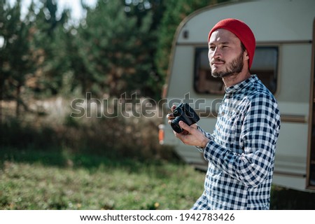 Man with a camera taking a picture in nature near the trailer at home.