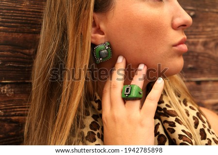 Blonde woman with jewelry on colorful background showing colorful ring and earring